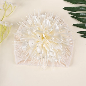Detailansicht eines cremefarbenen Baby-Turbans mit großer Satin-Kamelie und Glitzersteinen