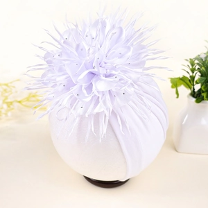 Close-up of baby white turban hat with a large layered flower and sparkling rhinestone