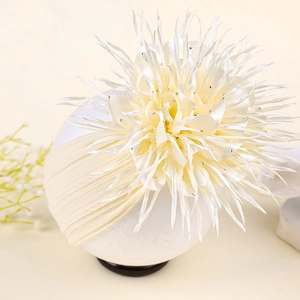 Vue détaillée d'un bandeau pour bébé en nylon crème avec une grande fleur strassée