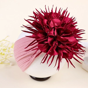 Gros plan sur la fleur en satin bordeaux avec strass sur un bandeau bébé en maille rose