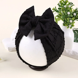 Vue détaillée du bandeau bébé noir avec tissu en maille texturé à bulles et grand nœud