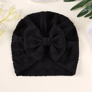 Détail d'un turban bébé en maille gaufre noire avec un grand nœud et texture douce