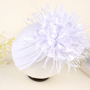 Détail d'un bandeau blanc pour bébé avec une grande fleur en satin, strass et plumes