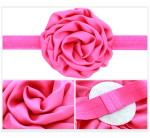 Detail view of handmade satin rose flower headband for infants in hot pink color
