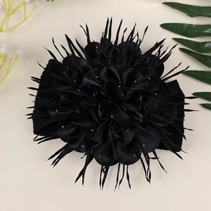 Détail d'un bandeau à grande fleur noire en satin avec strass et décorations en plumes