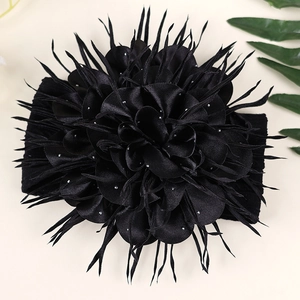 Détail d'un bandeau à double fleur noire orné de strass brillants et de plumes élégantes