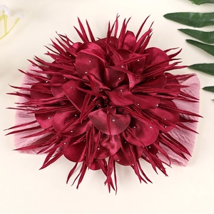 Détail du bandeau fleur en satin bordeaux avec perles argentées et ruban rose élastique