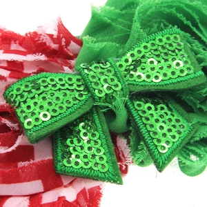 Detail of Christmas headband with green sequin bow and red white plaid fabric textures