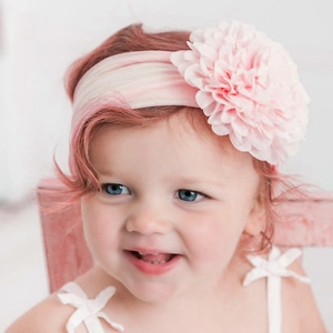 Bandeau bébé avec fleur en mousseline rose sur un modèle de nourrisson pour la tête