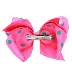Détail d'un nœud en ruban gros-grain rose à pois verts avec pince crocodile en métal