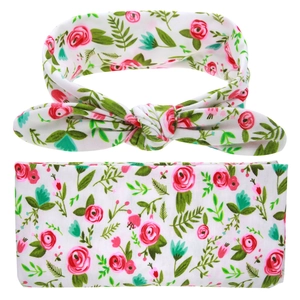 Close-up of floral baby headband featuring pink roses and green leaves on white fabric