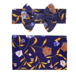 Detailed view of soft floral baby swaddle blanket and matching bow headband set in navy blue