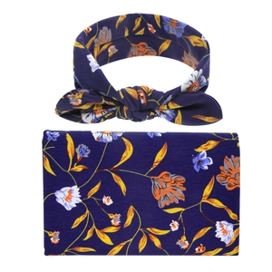 Detailed view of floral baby swaddle blanket and matching bow headband in navy blue fabric