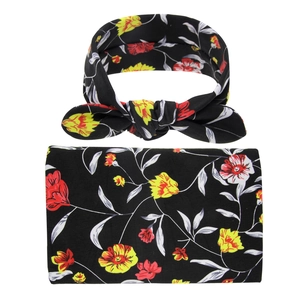 Detailed close-up of floral baby headband with matching bow and soft knit swaddle fabric