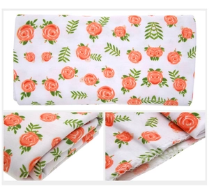 Detail of baby swaddle blanket featuring orange roses and fine three-thread lockstitch edges