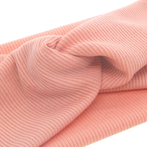 Pink knitted baby headband featuring a soft ribbed texture and a stylish cross knot design