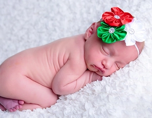 Close-up of baby wearing a festive red, green and white chiffon flower headband with rhinestones