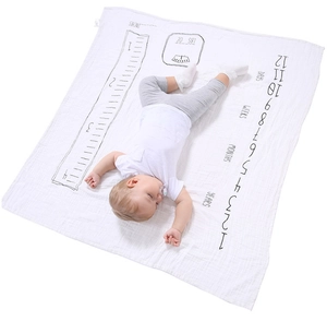Detailed overhead shot of a white baby milestone blanket with measurement scales and units