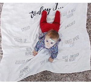 Detailed shot of white cotton baby milestone blanket with black cursive text prints