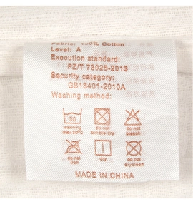 Detail shot of care label on white 100% cotton baby swaddle with washing icons