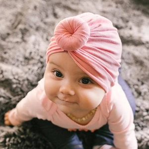 Close-up of pink knit newborn baby turban featuring a stylish top knot ring detail