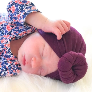 Detailed close-up of dark purple newborn turban hat with a circular knot and soft texture