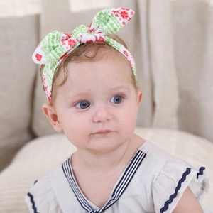 Close-up of baby wearing a white headband with red snowflake bow and Nordic patterns