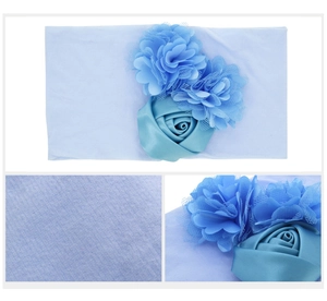 Détail d'un bandeau bébé bleu clair montrant la texture douce et les fleurs 3D appliquées