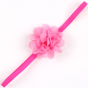 Dettaglio di un fiore in chiffon rosa acceso su una morbida fascia elastica per neonati