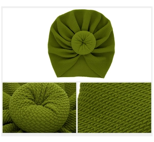 Close-up of olive green waffle knit baby turban hat with a large donut knot detail