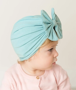 Detail of baby girl wearing mint green turban hat with large bow decoration
