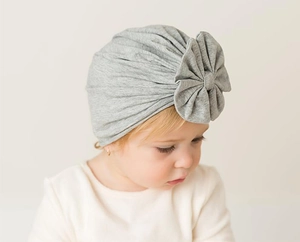 Detail of baby turban hat in grey with large bow on a soft newborn infant model