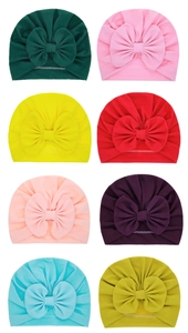 Detail view of baby turban hats showing a variety of eight solid colors with large bows