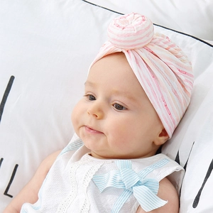 Detail of baby donut hat with pink and white stripes made of soft knitted fabric