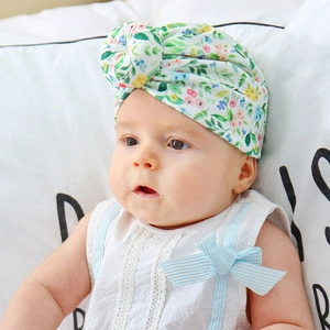Detail of floral print baby turban hat with top knot design on soft textured fabric
