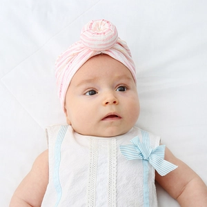 Close-up of pink and white striped baby turban featuring a top knot decorative ball