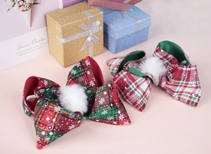 Details von rot-grün karierten Weihnachts-Haarschleifen mit Pelzkugeln auf Geschenkbox