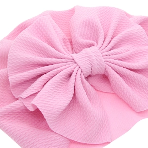 Pink baby turban with large bow made of bubble fabric texture on a white background
