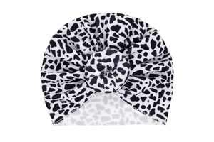 Detail view of cotton baby turban hat with cow print pattern and top knot decoration