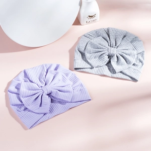 Detail of soft ribbed knit cotton baby turbans with oversized bows in purple and grey