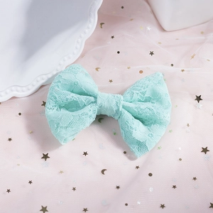 Dettaglio ravvicinato di un fiocco per capelli in pizzo verde menta su tulle rosa stellato
