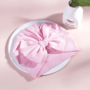 Close-up of baby pink ribbed cotton turban hat with a large decorative bow