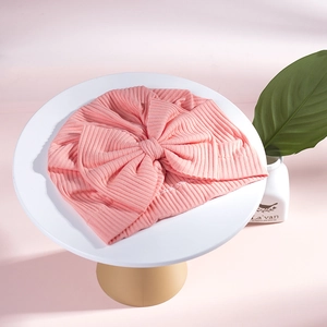 Detailed view of baby pink ribbed cotton turban hat with a large decorative bow
