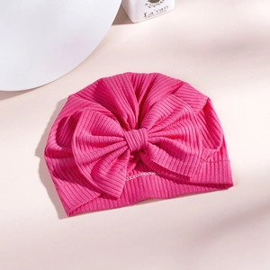 Detail of baby turban hat with ribbed knit fabric and a large decorative bow in rose pink