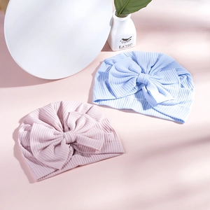 Close-up of soft ribbed cotton baby beanies with large decorative bow in pink and blue