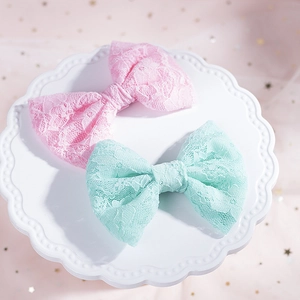 Dettaglio di fermagli per capelli con fiocchi in pizzo rosa e verde su piatto in ceramica