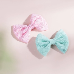Dettaglio dei fermagli per capelli con fiocchi in pizzo rosa pastello e menta