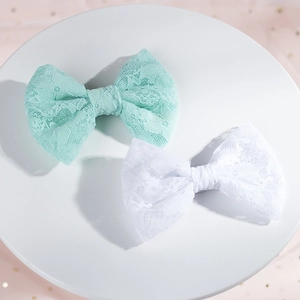 Dettaglio dei delicati fermagli per capelli in pizzo verde menta e bianco con trama floreale