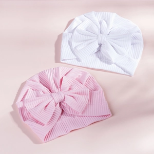 Detail of pink and white ribbed cotton baby turban hats with large decorative bows