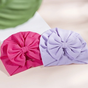 Detail of ribbed knit baby turban hats with large bows in magenta and lilac colors